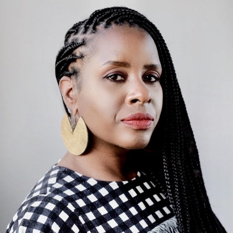 head shot of a woman with long dark braids wearing gold earrings and a black and white dress