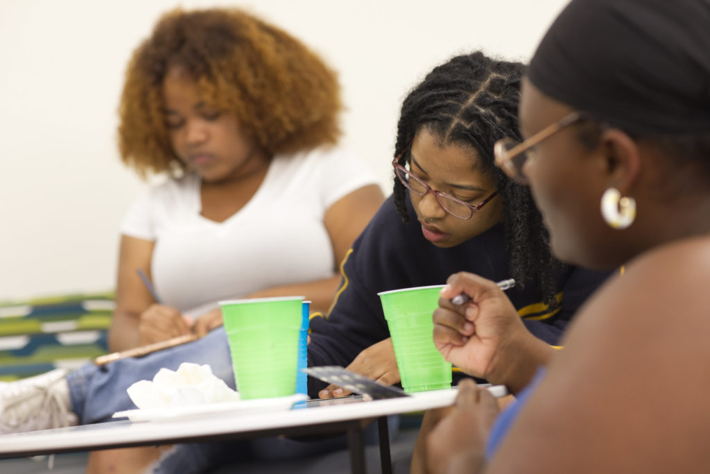 Three AAAS students work at a table.