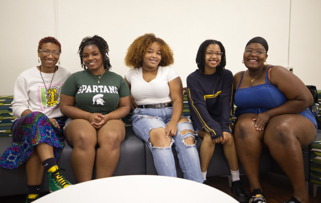 Five smiling AAAS students sit on a couch.