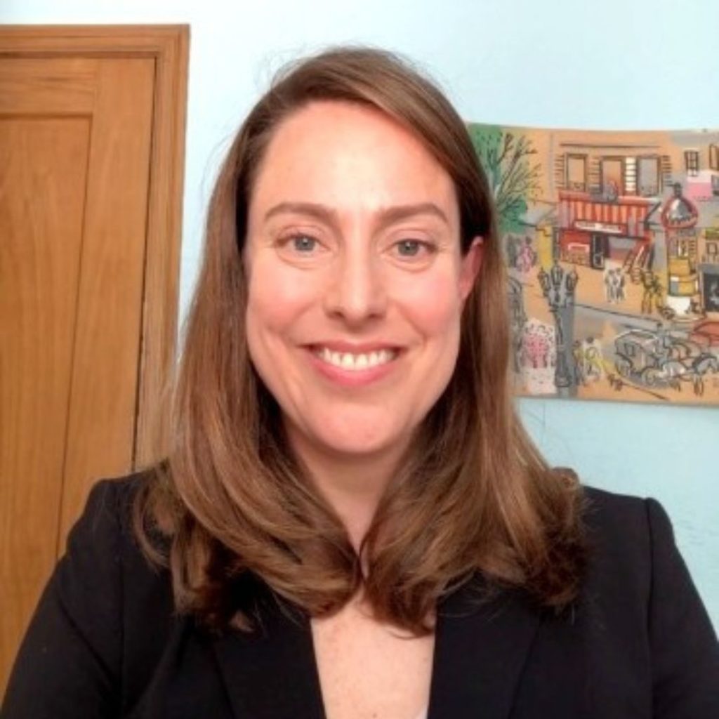 Portrait of a smiling woman with short brown hair wearing a black blazer.